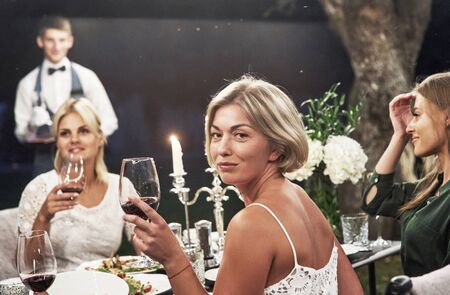 Unexpected portrait view. Group of adult friends have a rest and conversation in the backyard of restaurant at evening time.の写真素材