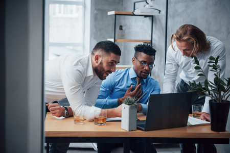 Serious man fully concentrated. Multiracial business people with laptop solving the company issues.