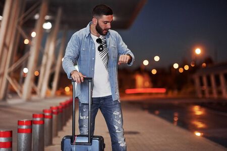 Man with short hair and travel baggage waiting for the taxi to pick him up.の写真素材