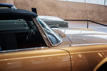 Side, lose up view of beige retro cabriolet car with steering wheel, chrome window trim and windshield washer, arch above a tire.の写真素材
