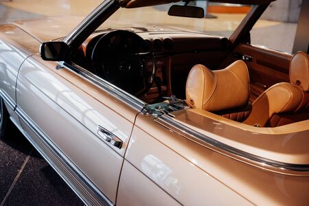 Side, close up view of beige retro cabriolet car leather interior and hood: steering wheel, dashboard, rear mirror and windshield.の写真素材