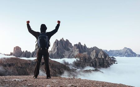 Touristic man raised his hands up on the beautiful daylight mountains full of fog.の写真素材