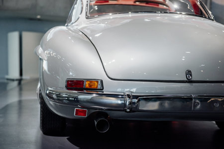 Photo from the back. White historical expensive retro car standing on the stand.