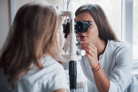 Process of diagnosing eye dysfunctions by female oculist with special equipment.