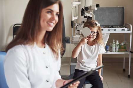 Well going. Doctor and little patient sits and conduct the test of the acuity of vision.