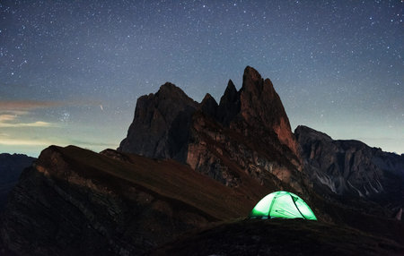 Dawned sun. Night photo of Seceda dolomites mountains. Tourists resting in the green tent.の写真素材