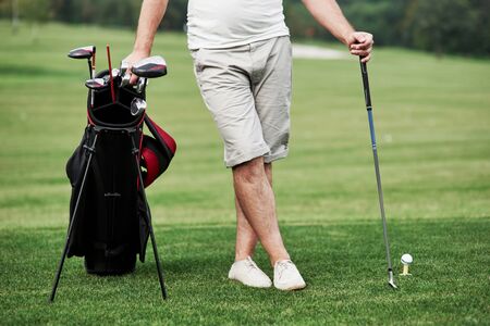 Part view of man standing on the green grass with golf equipment.の写真素材
