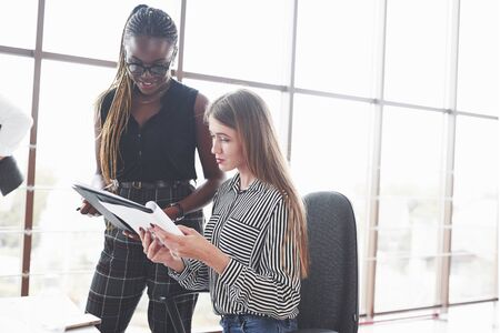 Two multiracial women are satisfied about the document that they made.の写真素材