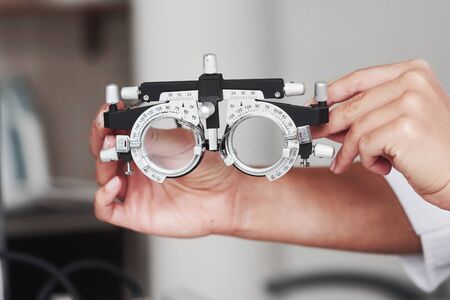 Focused photo. Female hands holding the optical device for eye testing.の写真素材
