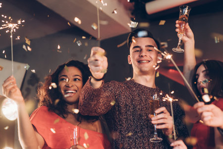 Joyful and happiness. Multiracial friends celebrate new year and holding bengal lights and glasses...