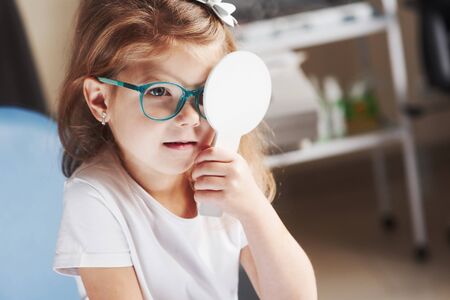 Holds by herself the occluder. Little girl checking his vision with new green glasses.の写真素材