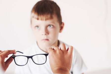 Attension to the eyewear. Doctor giving the child new black glasses for his vision.の写真素材