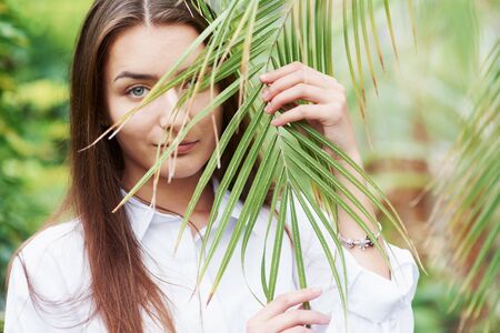 Gorgeous young woman holding the branch in the greenhouse.の写真素材