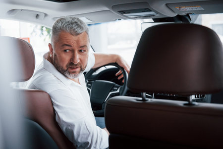 Driving a car in reverse gear. Looking behind. Man in his brand new automobile.