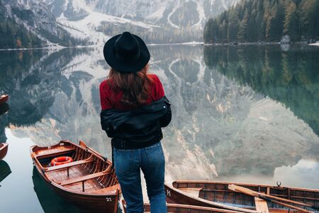 Gorgeous part of nature. Woman in black hat enjoying majestic mountain landscape near the lake with boats.の写真素材