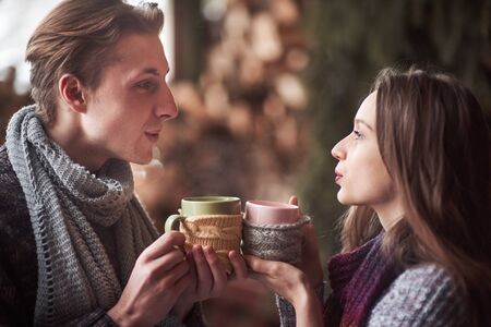 Photo of happy man and pretty woman with cups outdoor in winter. Winter holiday and vacation. Christmas couple of happy man and woman drink hot wine. Couple in love.の写真素材