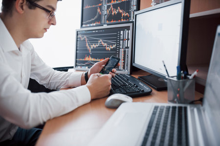 Stockbroker in shirt is working in a monitoring room with display screens. Stock Exchange Trading...
