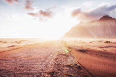 Fantastic sunset of the mountains and volcanic lava sand dunes to the beach in Stokksness. the...