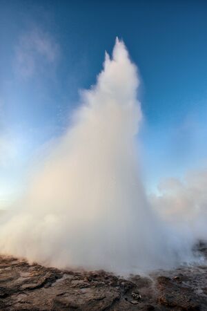 Strokkur geyser eruption in Iceland. Fantastic colors shine through the steam. Beautiful pink clouds in a blue sky.の写真素材
