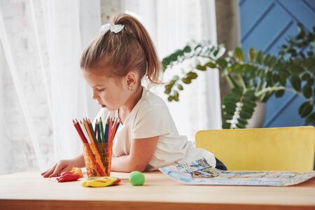How to busy your kid. Cute little girl in art school draws her first paintings by pencils and markers.の写真素材