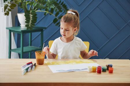 Variety of colours. Little girl is drawing by using gouache and brush. Learning in the art class.の写真素材