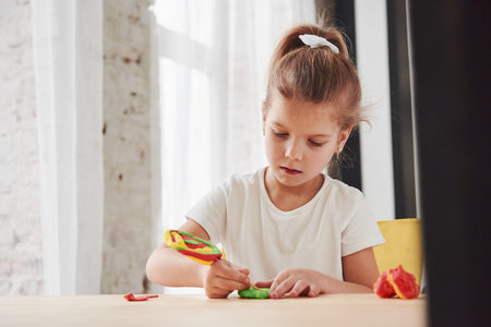 Using stick from artificial candy to make some new stuff. Children playing with colored plasticine on the wooden table at home.の写真素材