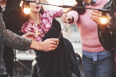 Lets ignite the party. Playing with sparklers on the rooftop. Group of young beautiful friends.の写真素材