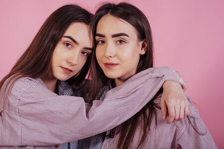 In harmony with each other. Two sisters twins standing and posing in the studio with white background.の写真素材