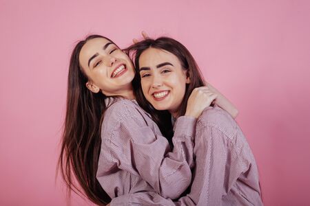 Sincere emotions. Two sisters twins standing and posing in the studio with white background.の写真素材
