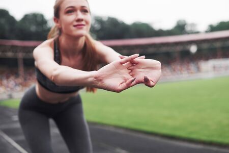 Morning stretches. Young blonde warming up on the track in the stadium at daytime.の写真素材