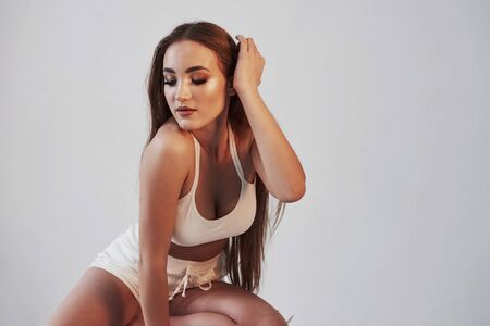 Model is touching her hair. Portrait of seductive brunette in the studio with white background.の写真素材