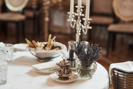Waits for visitors. Picture of served table with bread sticks, plant in the water and silver colored kettle.の写真素材