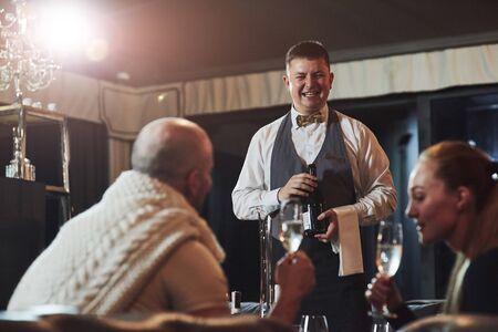 Waiter is smiling. Girl with her boyfriend have nice evening at beautiful restaurant.の写真素材