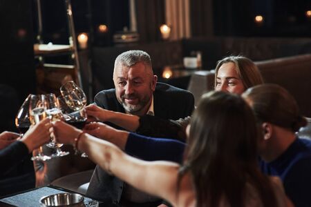 Cheers to all. Family friends having nice time in beautiful luxury modern restaurant.の写真素材