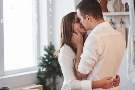 Happy couple kissing in the kitchen. Having nice weekend together.の写真素材