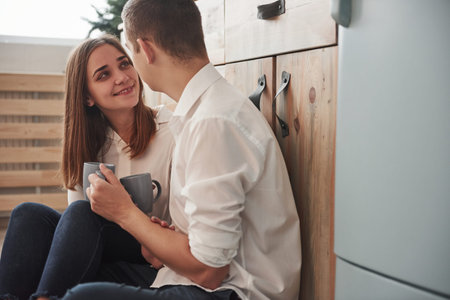 Husband with his wife relaxing by sitting on the kitchen and having good conversation.の写真素材