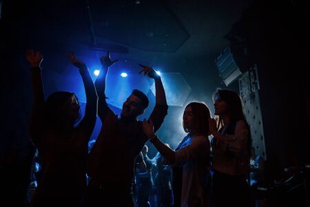 Happy youth. Group of people that enjoying dancing in the nightclub with beautiful lightings.の写真素材