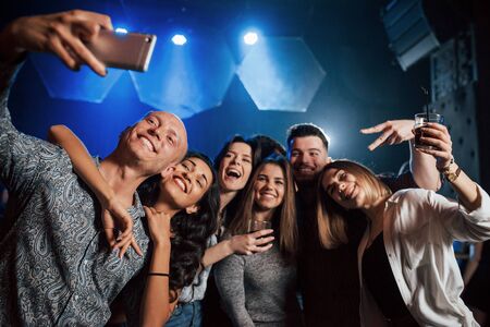 Look at the camera. Friends taking selfie in beautiful nightclub. With drinks in the hands.の写真素材