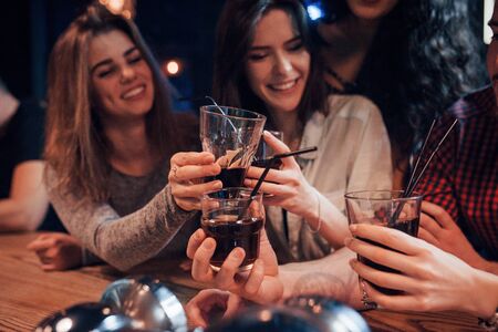 Perfect time spending for the youth. Group of young friends smiling and making a toast in the nightclub.の写真素材