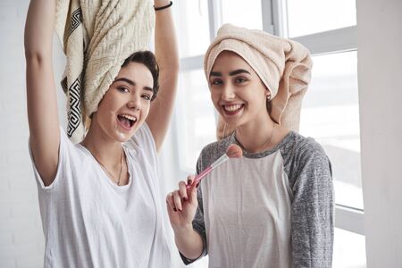 Playing around. Sisters have skincare using brush with powder. With towels on the heads.の写真素材