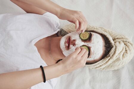 Top view of girl in white beauty mask on face and cucumber rings on eyes.の写真素材