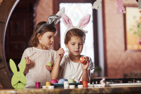 Look how I do it. Have happy easter. Two little girls learning how to paint eggs for the holidays.