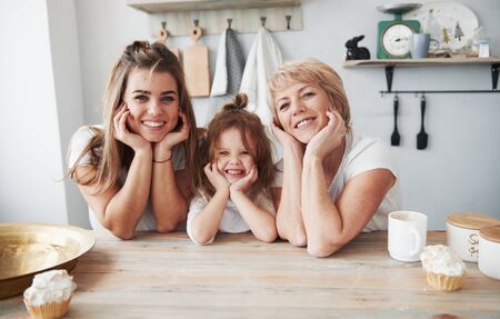 Nice portrait. Mother, grandmother and daughter having good time in the kitchen.の写真素材