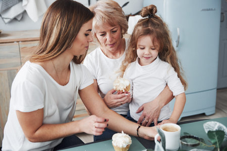 Coffee and sweet food. Mother, grandmother and daughter having good time in the kitchen.