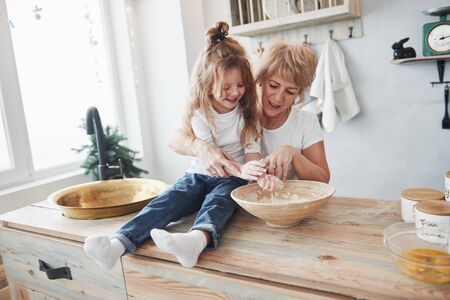 Preparing food goes fun. Grandmother and granddaughter having good time in the kitchen.の写真素材