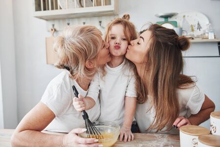 Lovely family. Mother, grandmother and daughter having good time in the kitchen.の写真素材