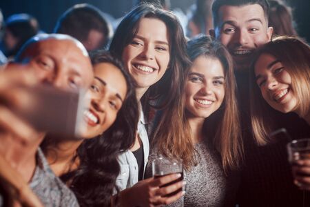 Such positive nice people. Friends taking selfie in beautiful nightclub. With drinks in the hands.の写真素材