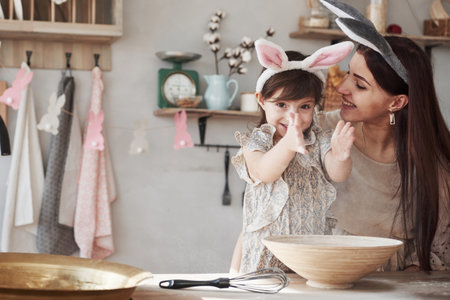 The child throws the flour. Mother and daughter in bunny ears at easter time have some fun in the...