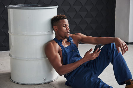 Spontaneous message. Time for the rest. African american man sits on the floor and leaning to the...