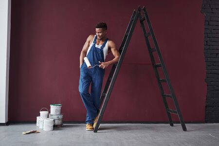 Looks at brushes. Young african american worker in the blue uniform have some job to do.の写真素材